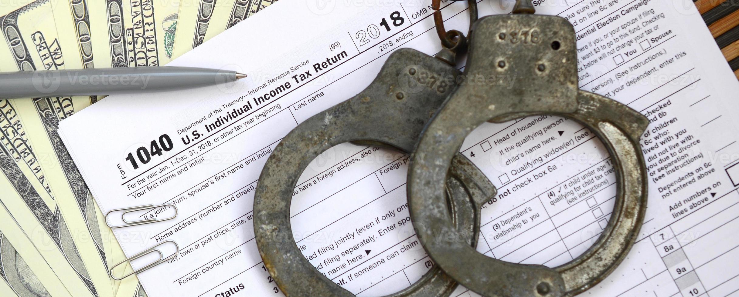 Police handcuffs lie on the tax form 1040. The concept of problems with the law in the aftermath of non-payment of taxes photo