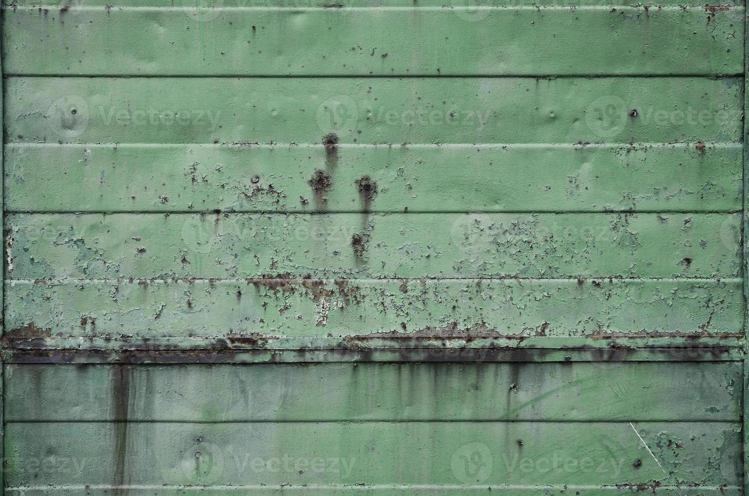 Texture of an old green metal wall with significant damage from exposure to unfavorable weather conditions and dampness photo