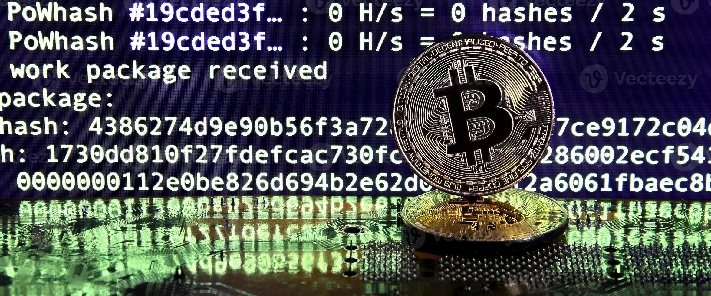 Two bitcoins lies on a videocard surface with background of screen display of cryptocurrency mining by using the GPUs photo