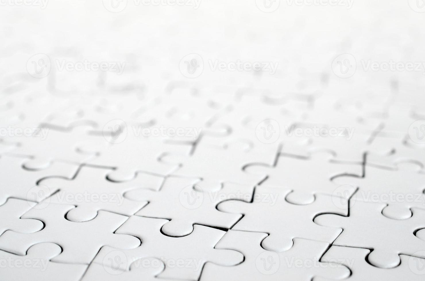 Close up of a white jigsaw puzzle in assembled state in perspective. Many components of a large whole mosaic are united photo