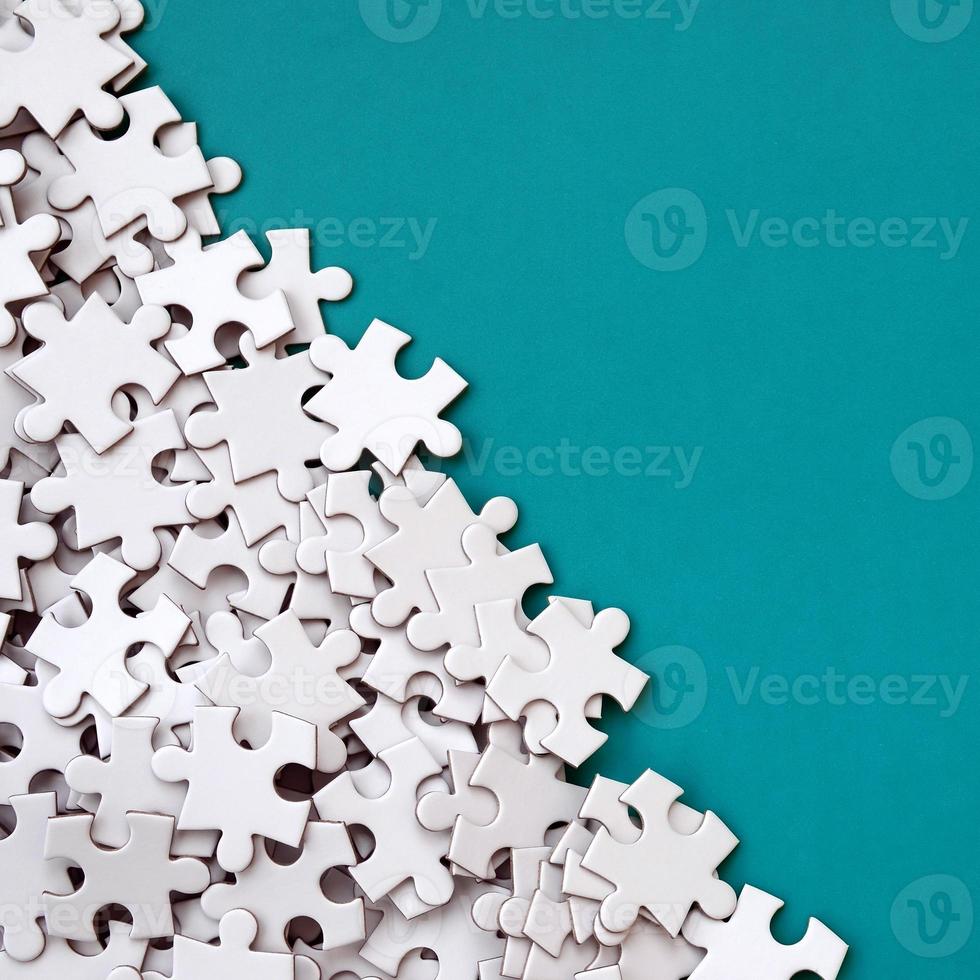 A pile of uncombed elements of a white jigsaw puzzle lies on the background of a blue surface. Texture photo with copy space for text