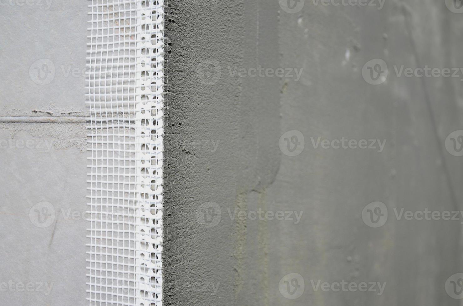 The texture of the wall, covered with gray polystyrene foam plates, which are coated with a reinforcing mixture with a plastic reinforcing profile corner. Stage of wall insulation photo