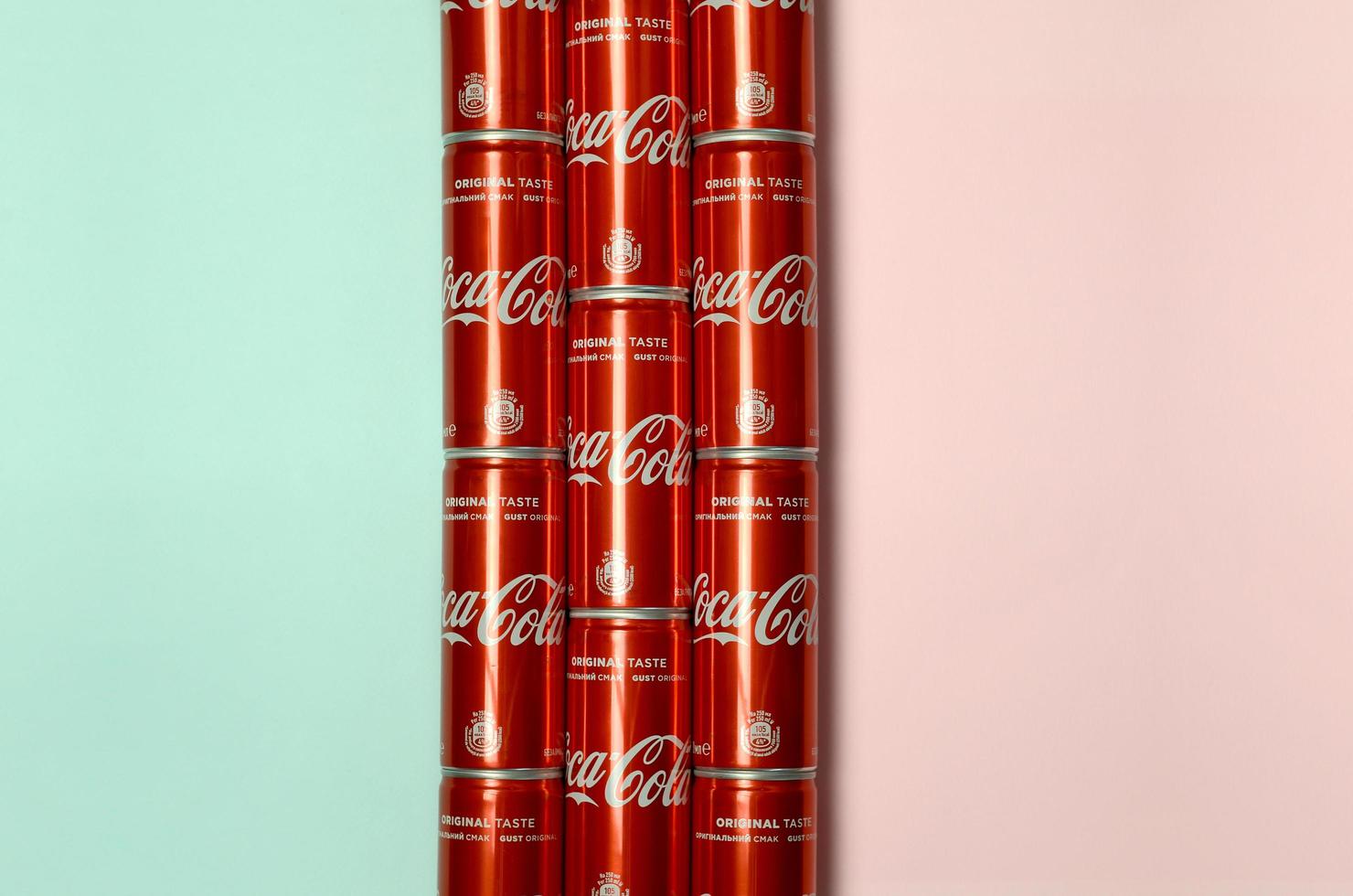 KHARKOV. UKRAINE - MAY 2, 2019 Flat lay shot carbonated red drink tin cans Coca Cola laying on pastel blue and coral background photo