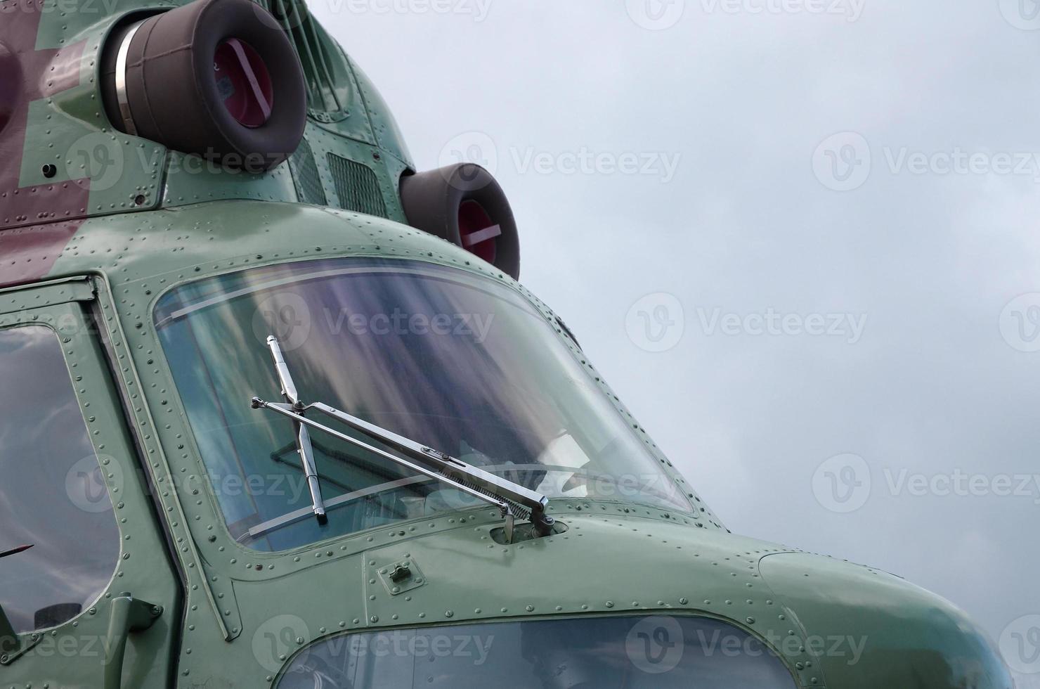 Helicopter cabin fragment close up. Camouflage aircraft fuselage and bulletproof glass photo