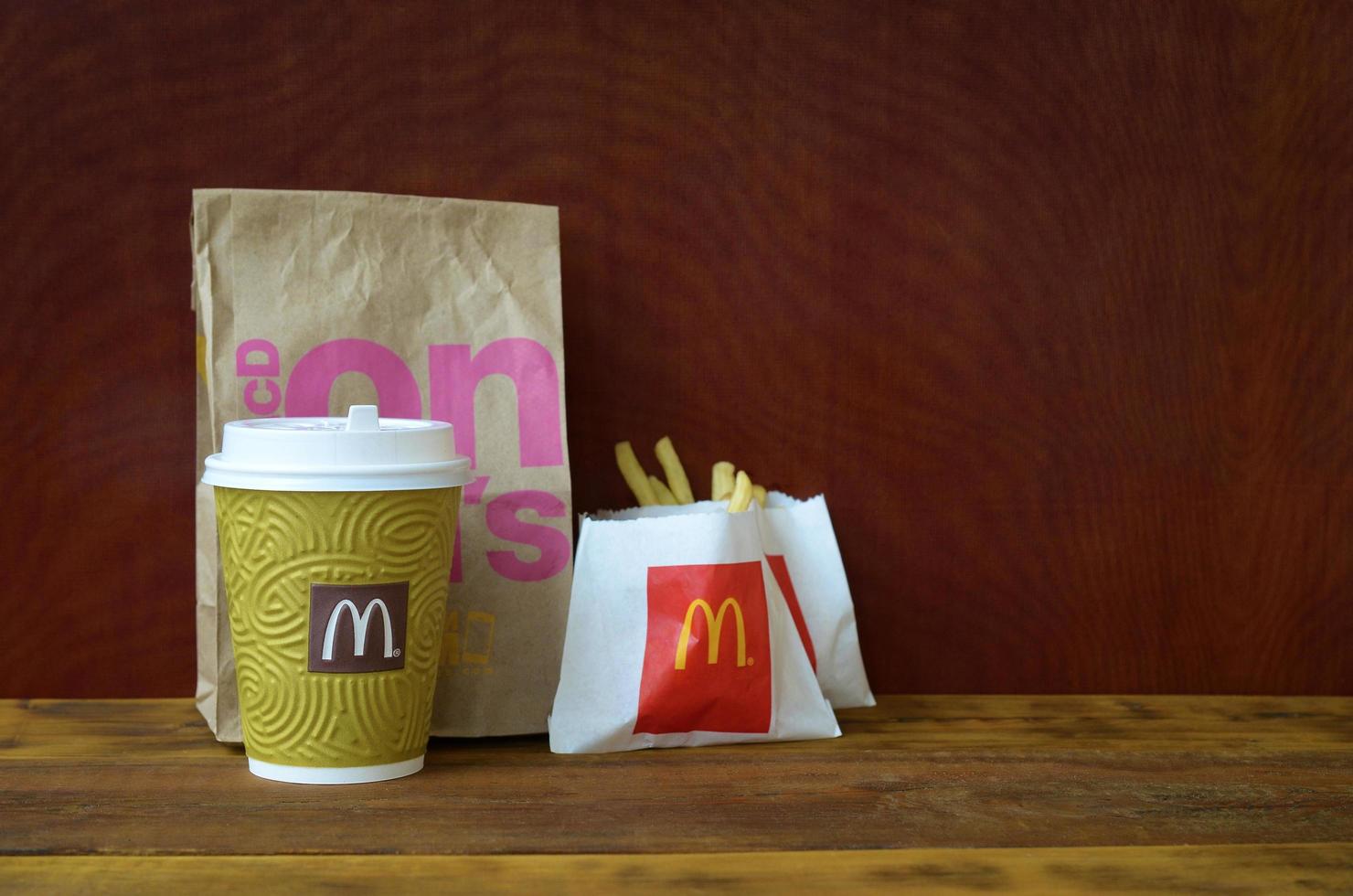 KHARKOV, UKRAINE - DECEMBER 9, 2020 McDonald's take away paper bag and junk food on wooden table photo