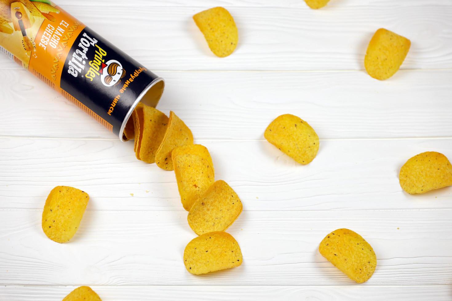 KHARKOV. UKRAINE - MAY 2, 2019 Pringles el nacho cheese flavour. Cardboard tube can with Pringles potato chips on white table. Pringles is a brand of snack chips owned by Kellogg Company photo