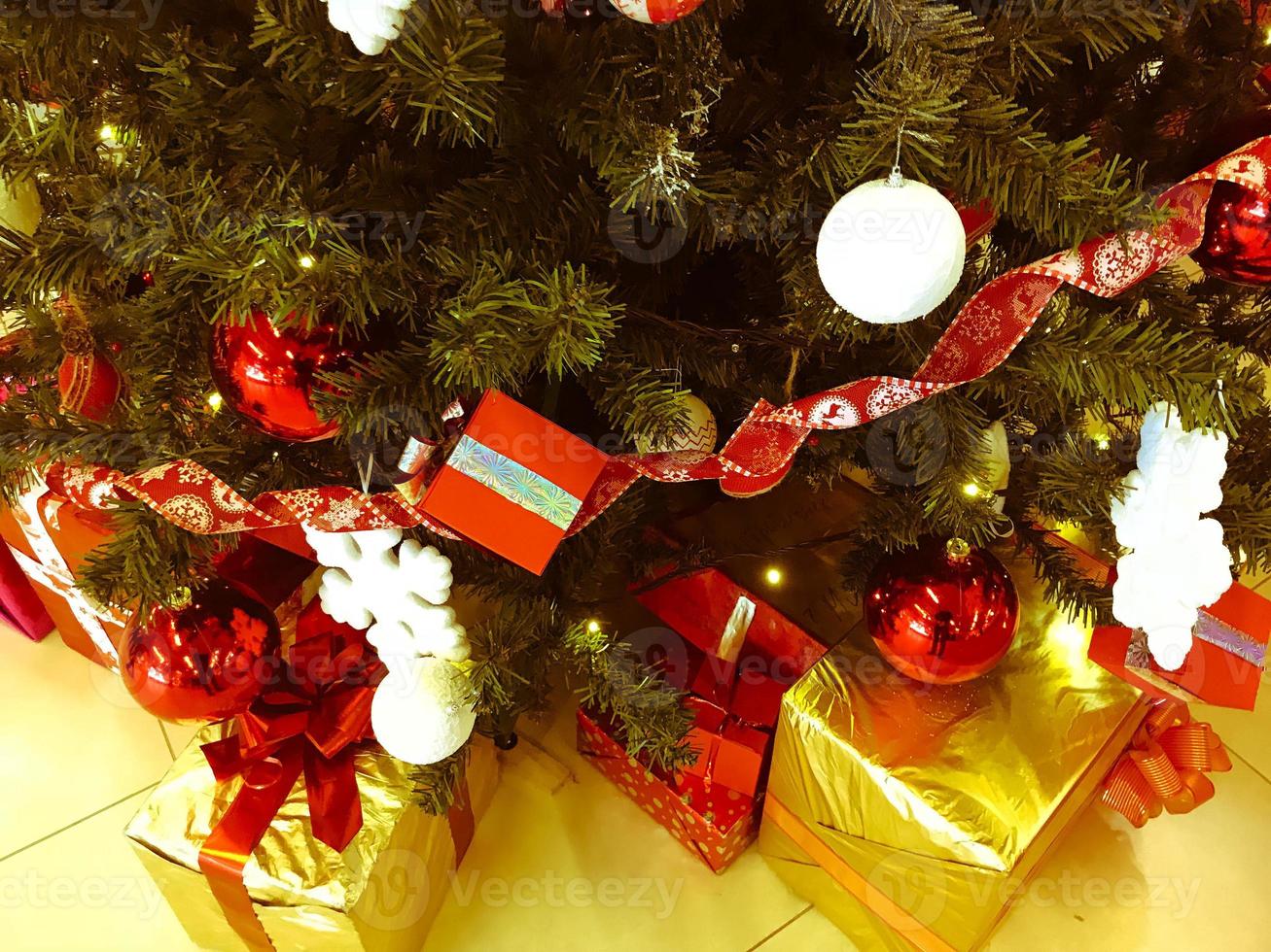 Festive colorful beautiful shiny gift boxes, decorations under the Christmas green tree with needles and branches, toys for the New Year. Background, texture photo