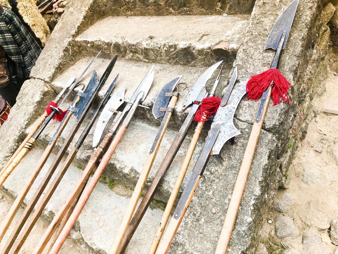 The old ancient medieval cold weapons, axes, halberds, knives, swords with wooden handles lick on the stone steps of the castle photo