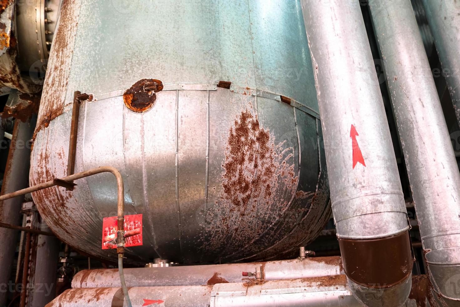 The large tank heat exchanger in insulation insulated by rust corrosion with holes is old at an industrial chemical oil refinery petrochemical plant photo