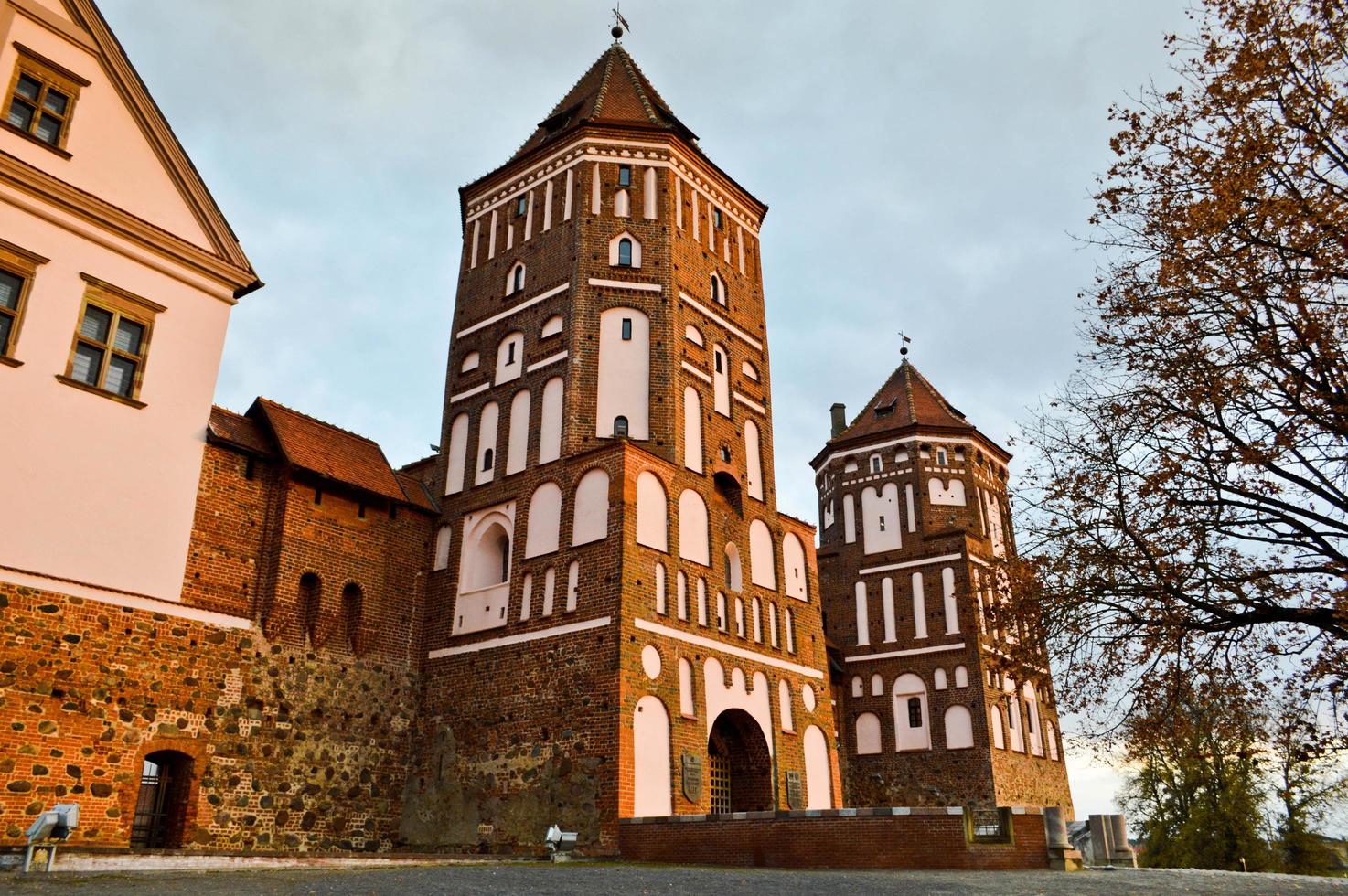 Old, ancient medieval castle with spiers and towers, walls of stone and brick surrounded by a protective moat with water in the center of Europe. Baroque style architecture photo