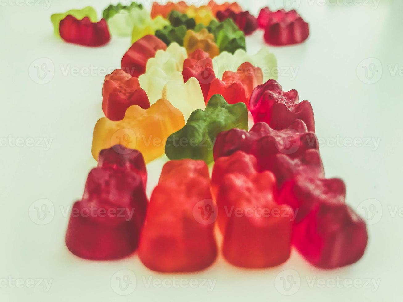 voluminous, bright gelatinous gummy bears. bears lie on a matte background. one row of bears. volumetric figure. bears are laid out in three rows. sweets for decorating cakes and pastries photo