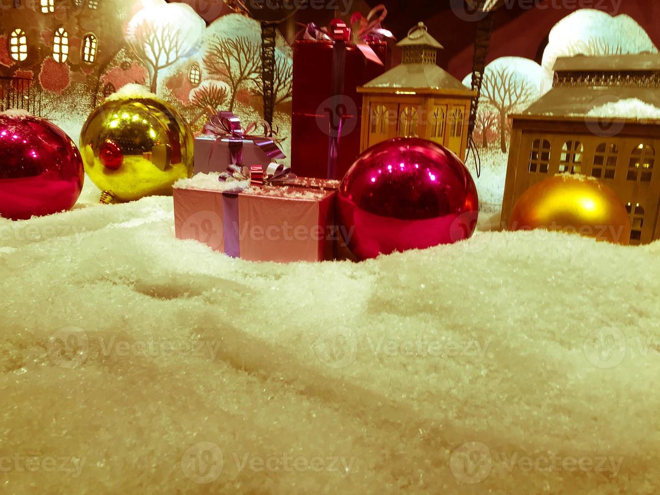 decoration for the showcase. round bright Christmas balls on artificial snow. next to gifts decorated with bright colored ribbons photo