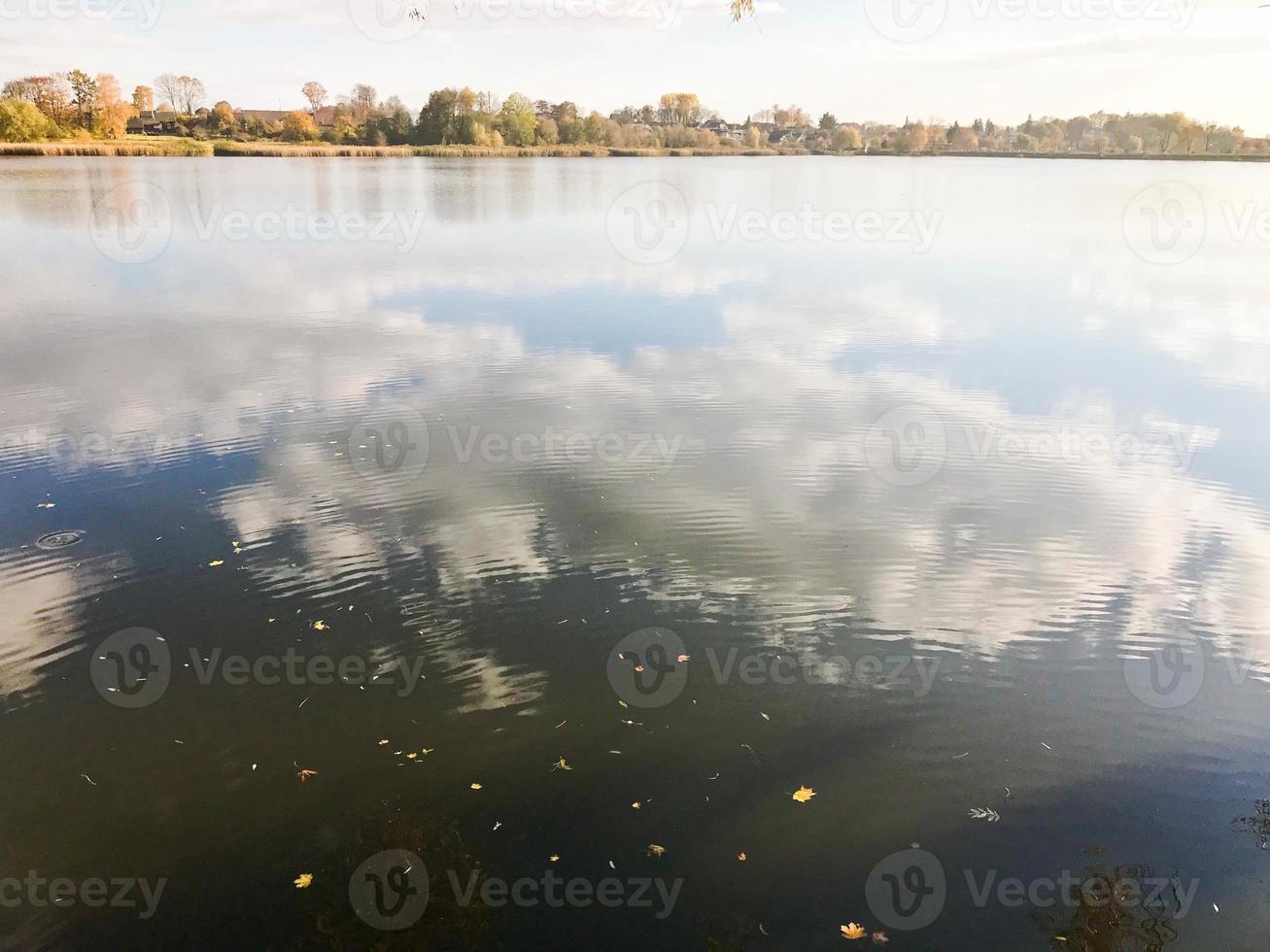 hermoso paisaje otoñal con árboles y hojas amarillas en el lago contra el cielo azul en un día soleado foto