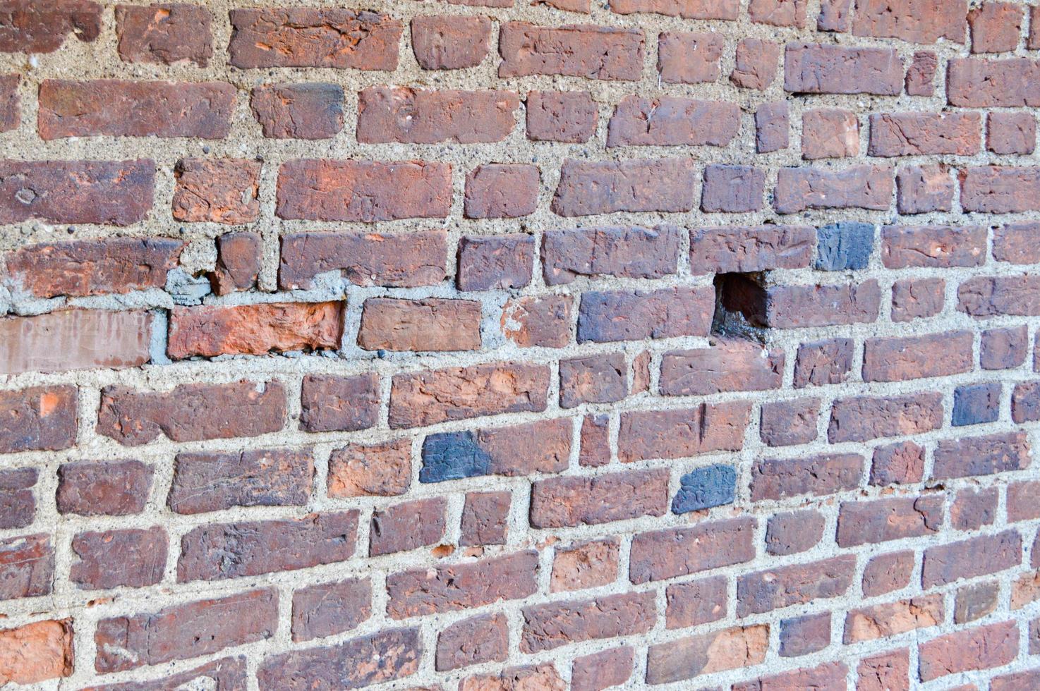 The texture of the old ancient medieval antique sturdy stone peeling scratched wall of rectangular red orange bright brick with seams and cracks. The background photo