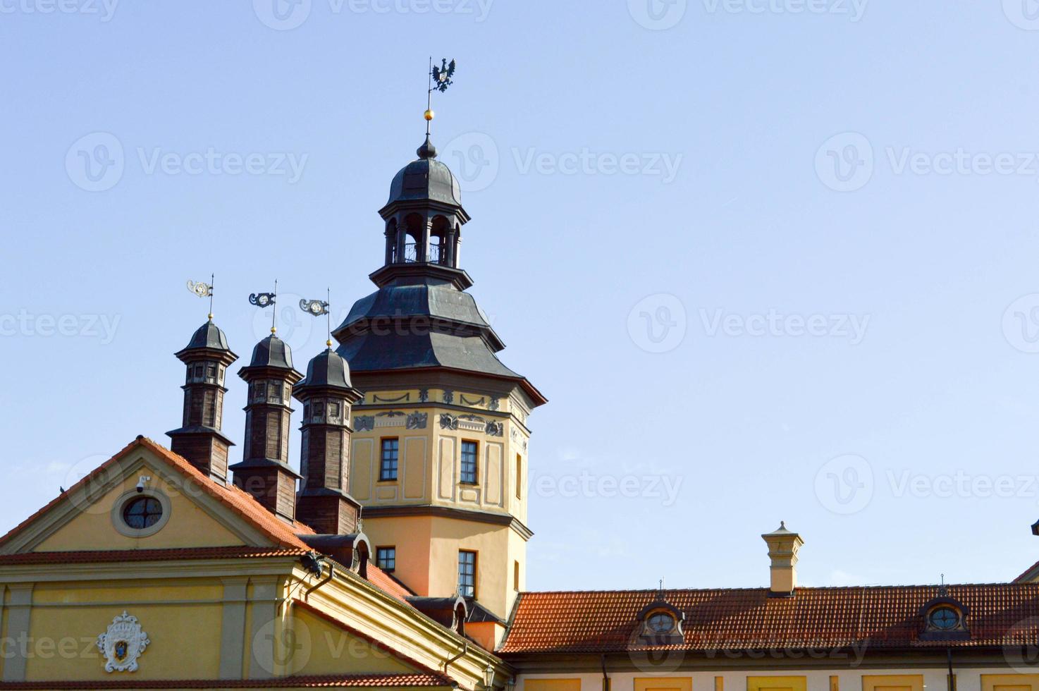 Tall steeples and towers, the roof of an old, ancient medieval baroque castle, a renaissance, Gothic in the center of Europe against a blue sky photo