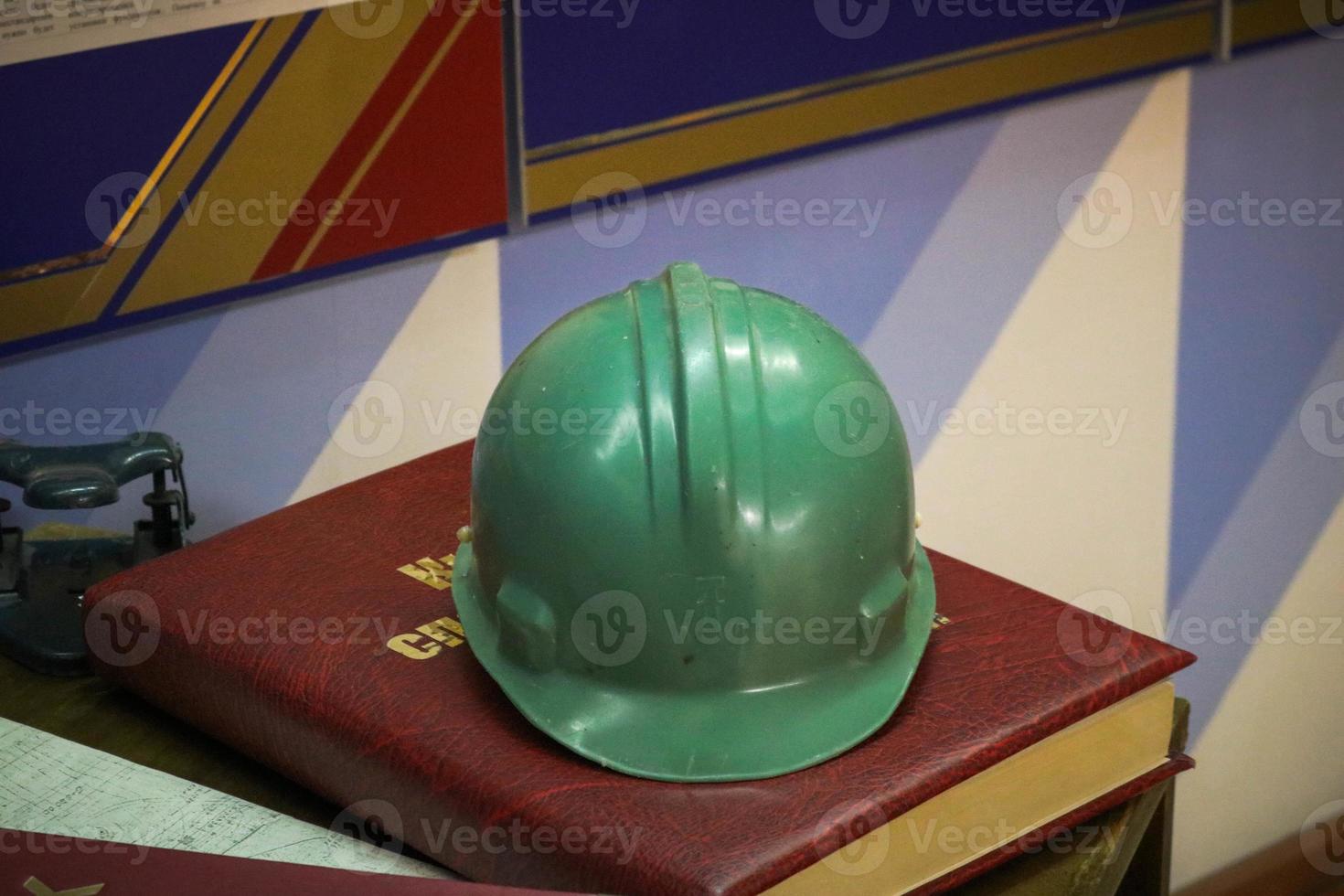 Green plastic safety helmet for the worker. Protective helmet to protect the head of people operating in hazardous conditions at the factory photo