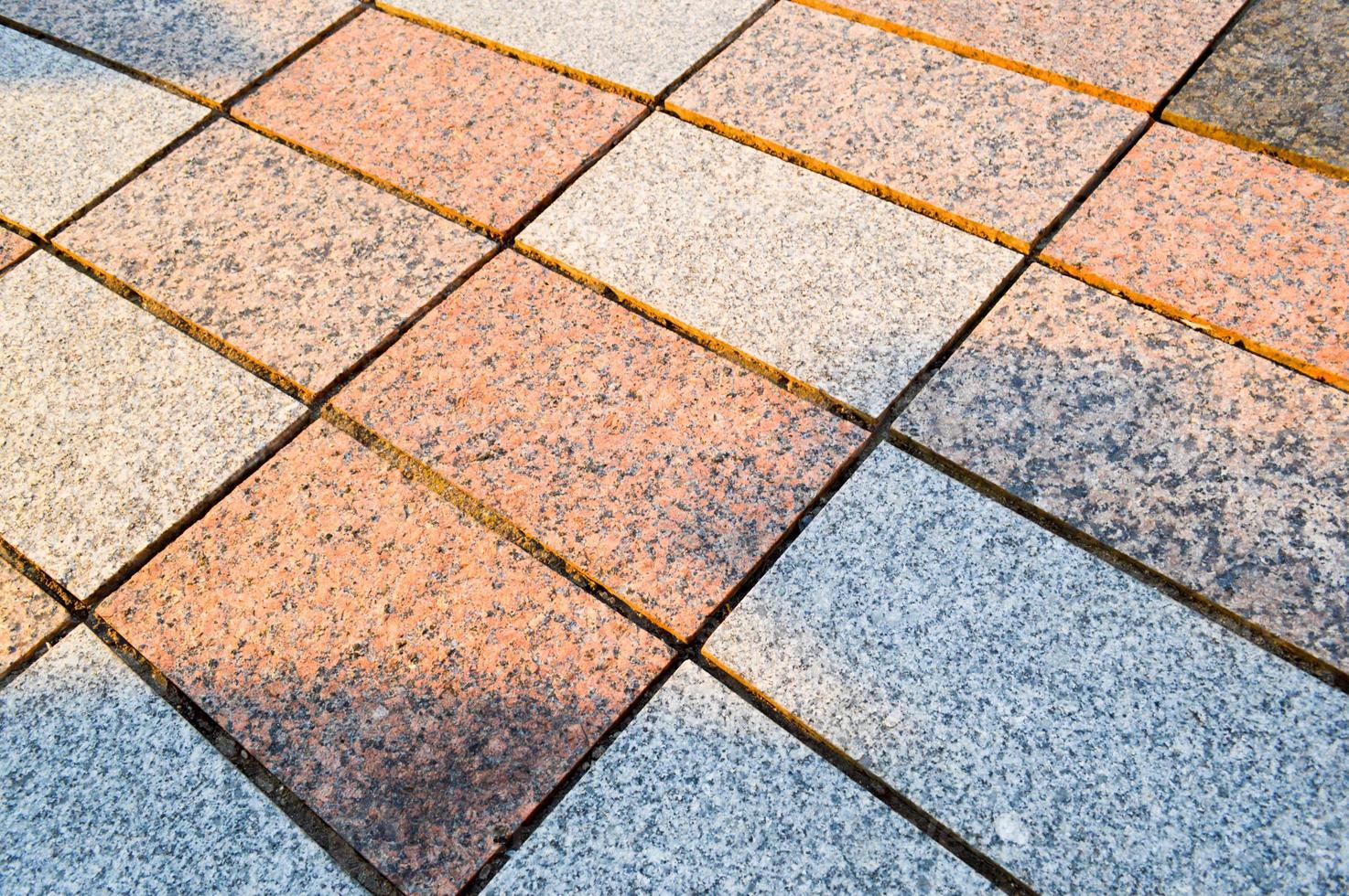 Texture of marble rectangular stone granite tiles with seams on the road. The background photo