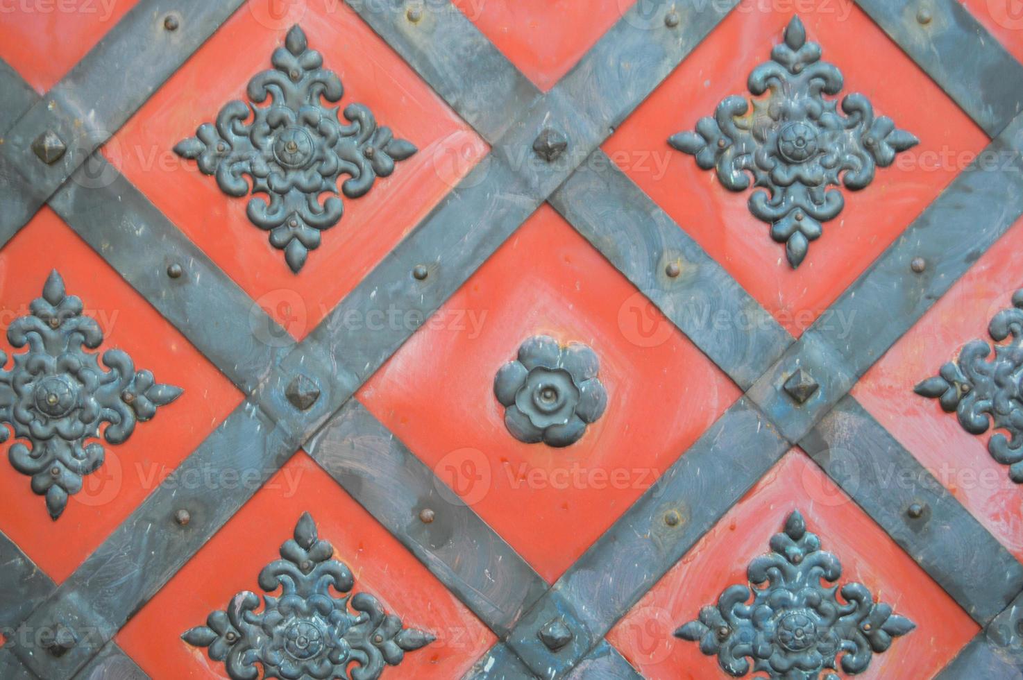 Texture of an old ancient medieval red antique sturdy iron metal door with rivets and nails patterns. The background photo