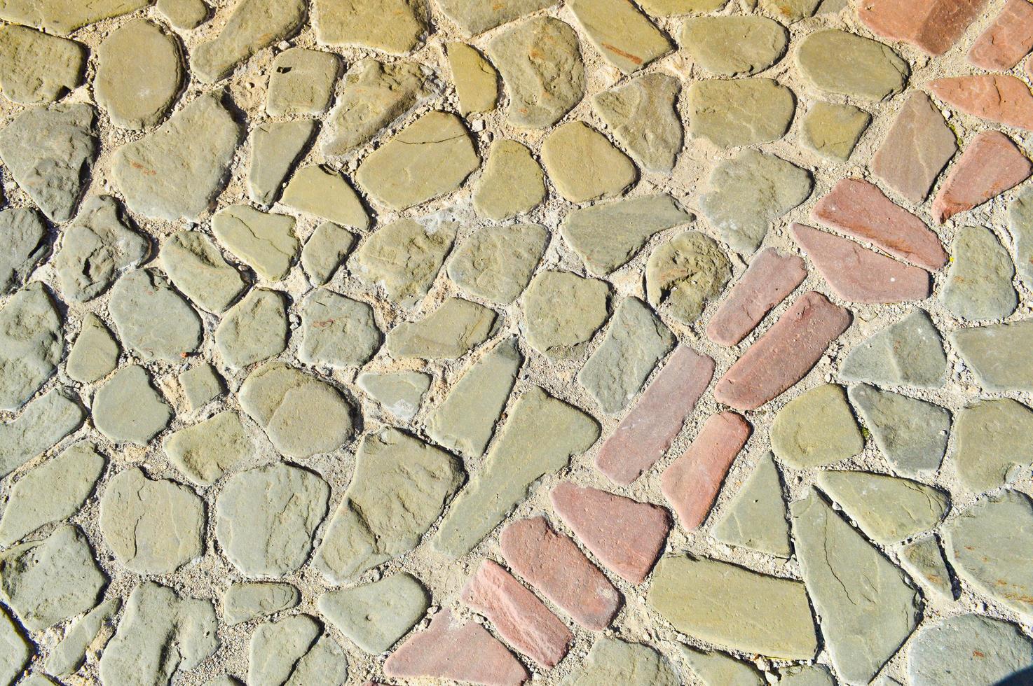 The texture of the stone road, pavement, walls of large gray old medieval round strong stones, cobblestones. The background photo