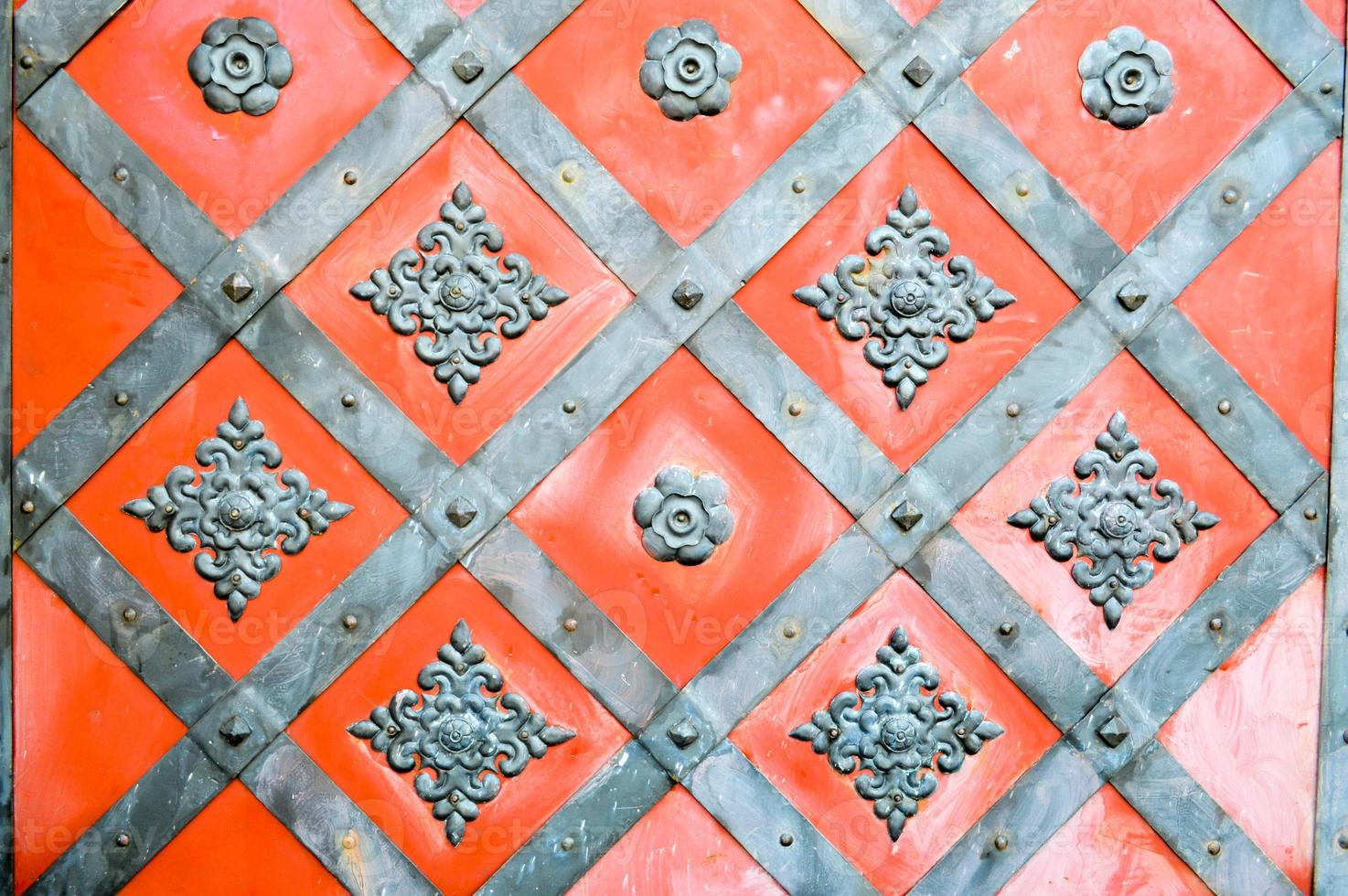 Texture of an old ancient medieval red antique sturdy iron metal door with rivets and nails patterns. The background photo