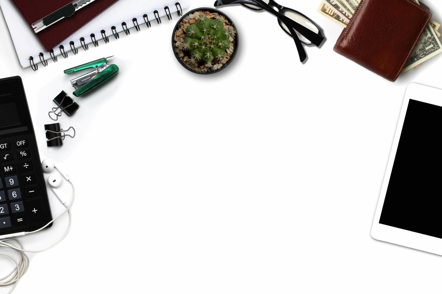 White office desk with tablet with black screen, calculator, wallet, and supplies. Top view with copy space photo