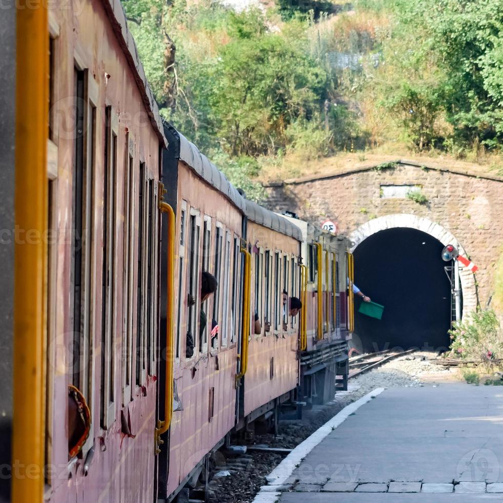 Toy Train moving on mountain slopes, beautiful view, one side mountain, one side valley moving on railway to the hill, among green natural forest. Toy train from Kalka to Shimla in India, Indian Train photo