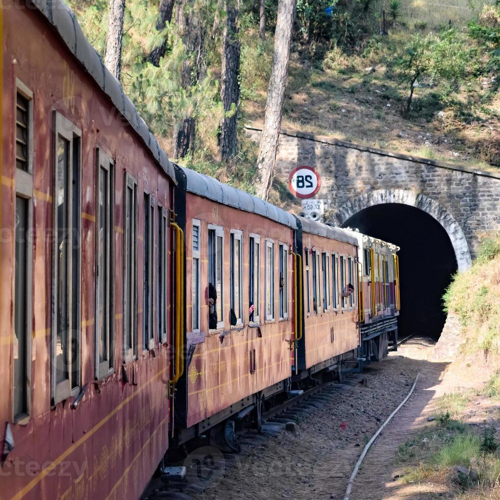 Toy Train moving on mountain slopes, beautiful view, one side mountain, one side valley moving on railway to the hill, among green natural forest. Toy train from Kalka to Shimla in India, Indian Train photo