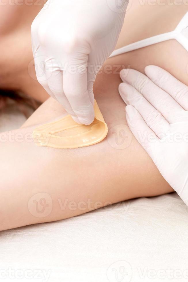 Cosmetologist applying wax paste on armpit photo