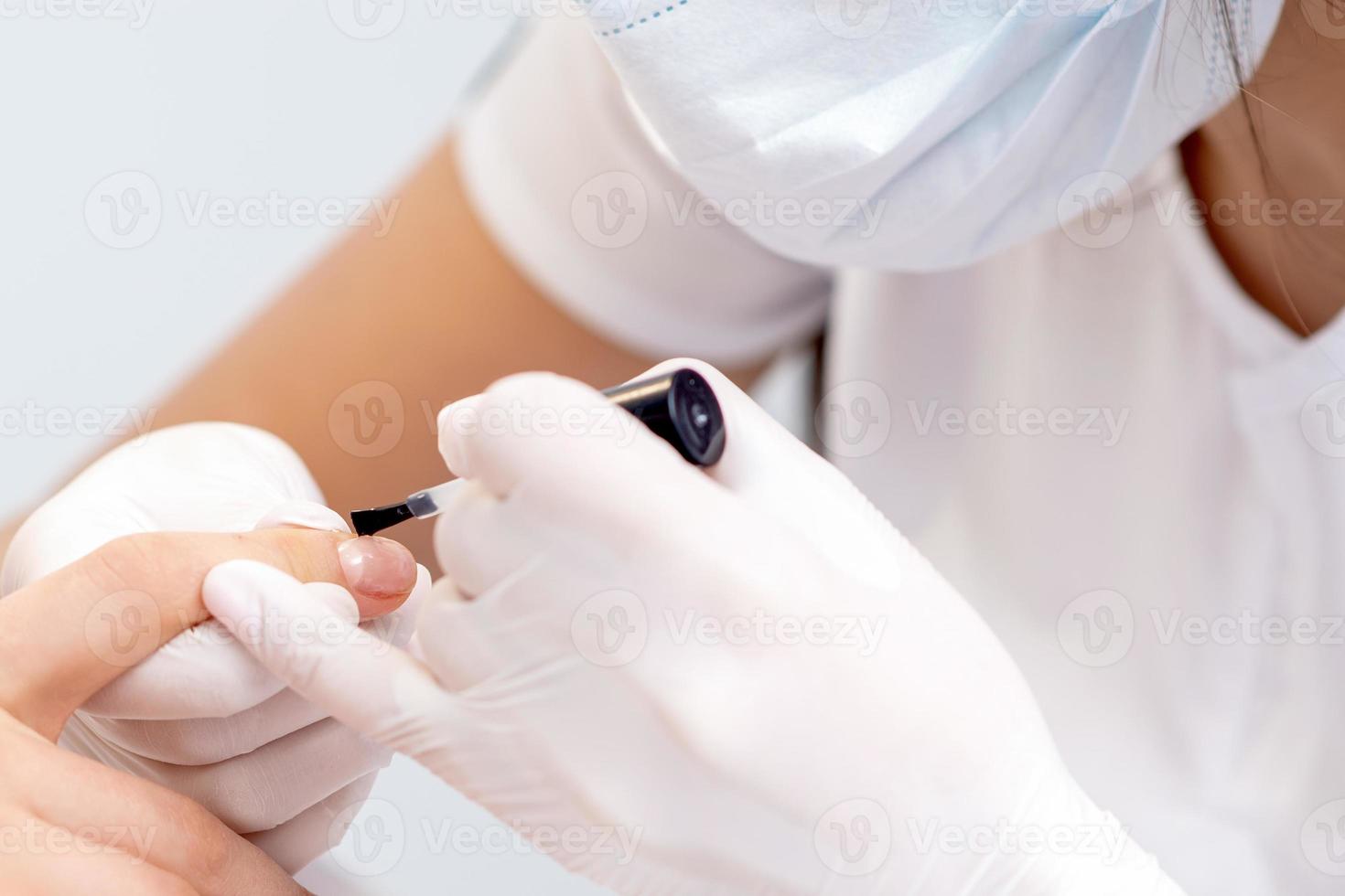 Human hands covering clear varnish on female nails photo