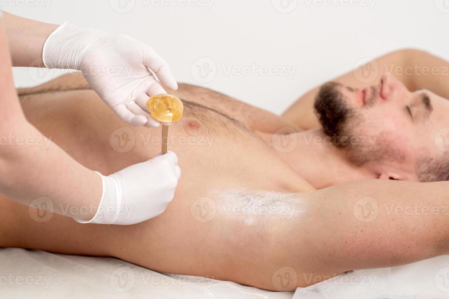 Cosmetologist applying wax paste on armpit photo