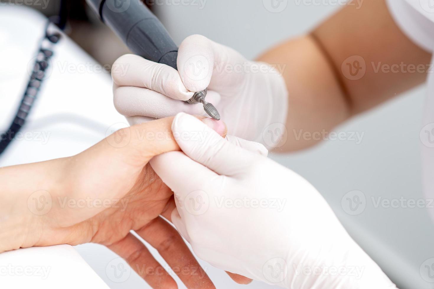 Manicure master uses an electric nail machine photo