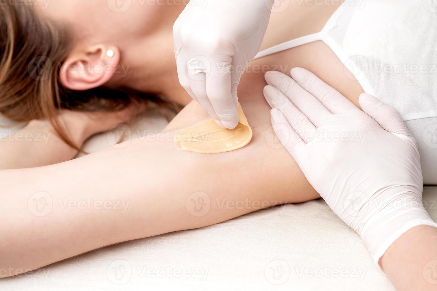 Cosmetologist applying wax paste on armpit photo