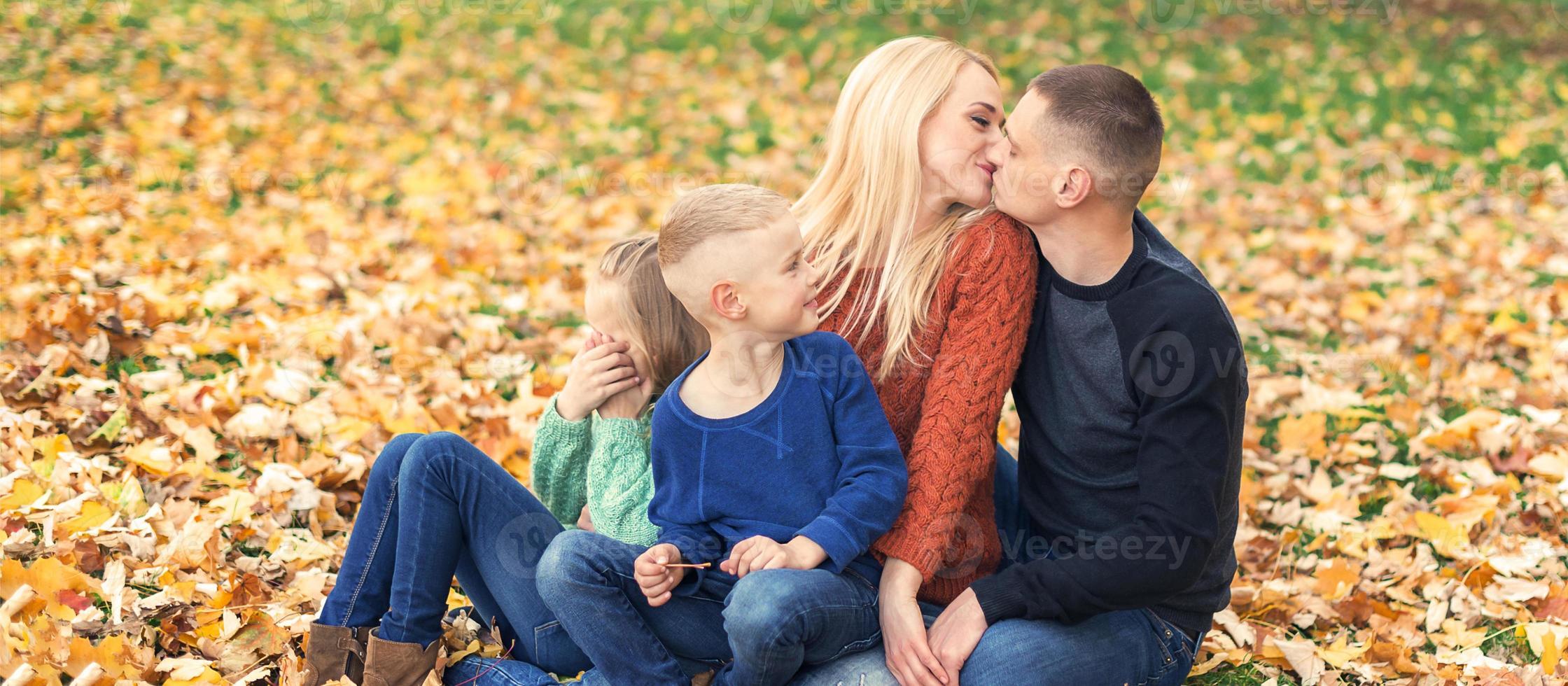 Portrait of young family sitting in autumn leaves photo