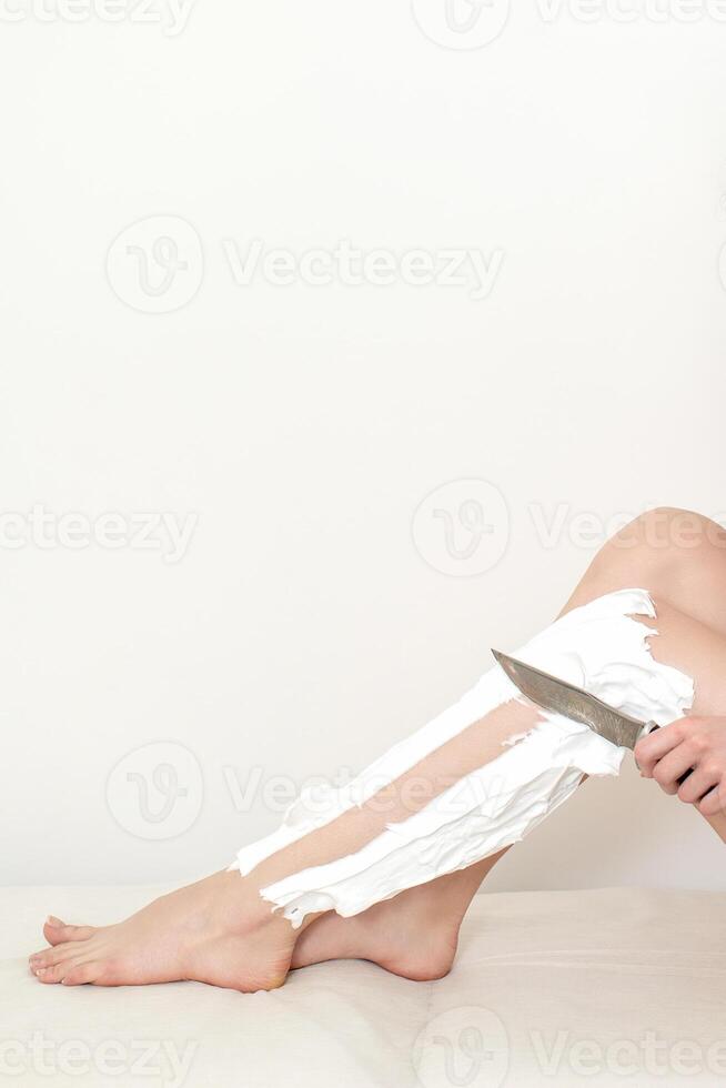 Woman shaves her legs with a knife photo