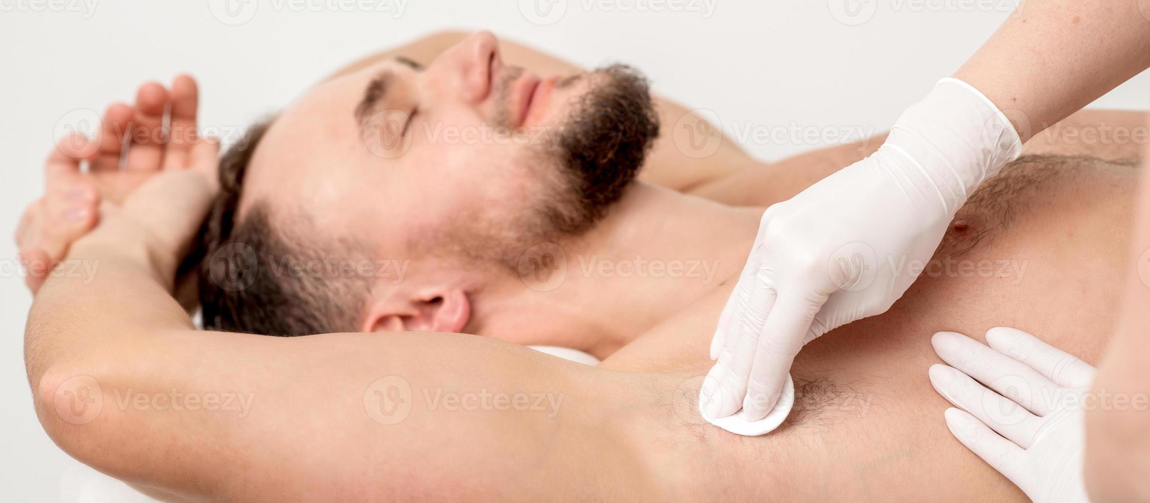 Depilation master wiping male armpit photo