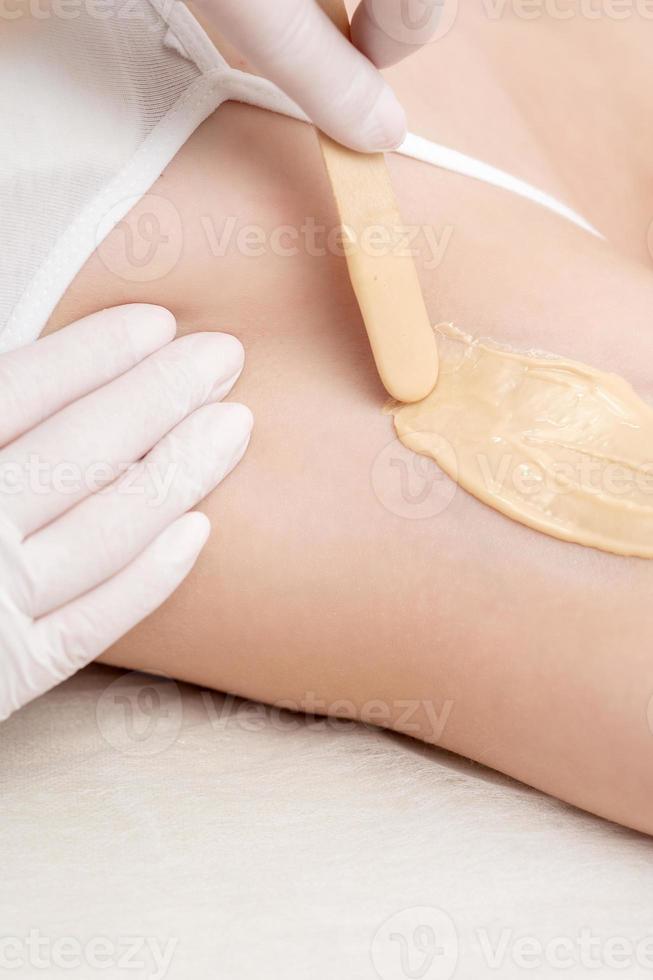 Cosmetologist applying wax paste on armpit photo