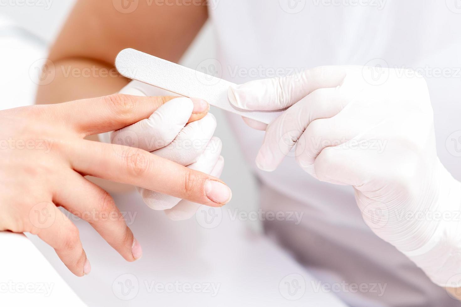 Young woman receiving manicure by nail file photo