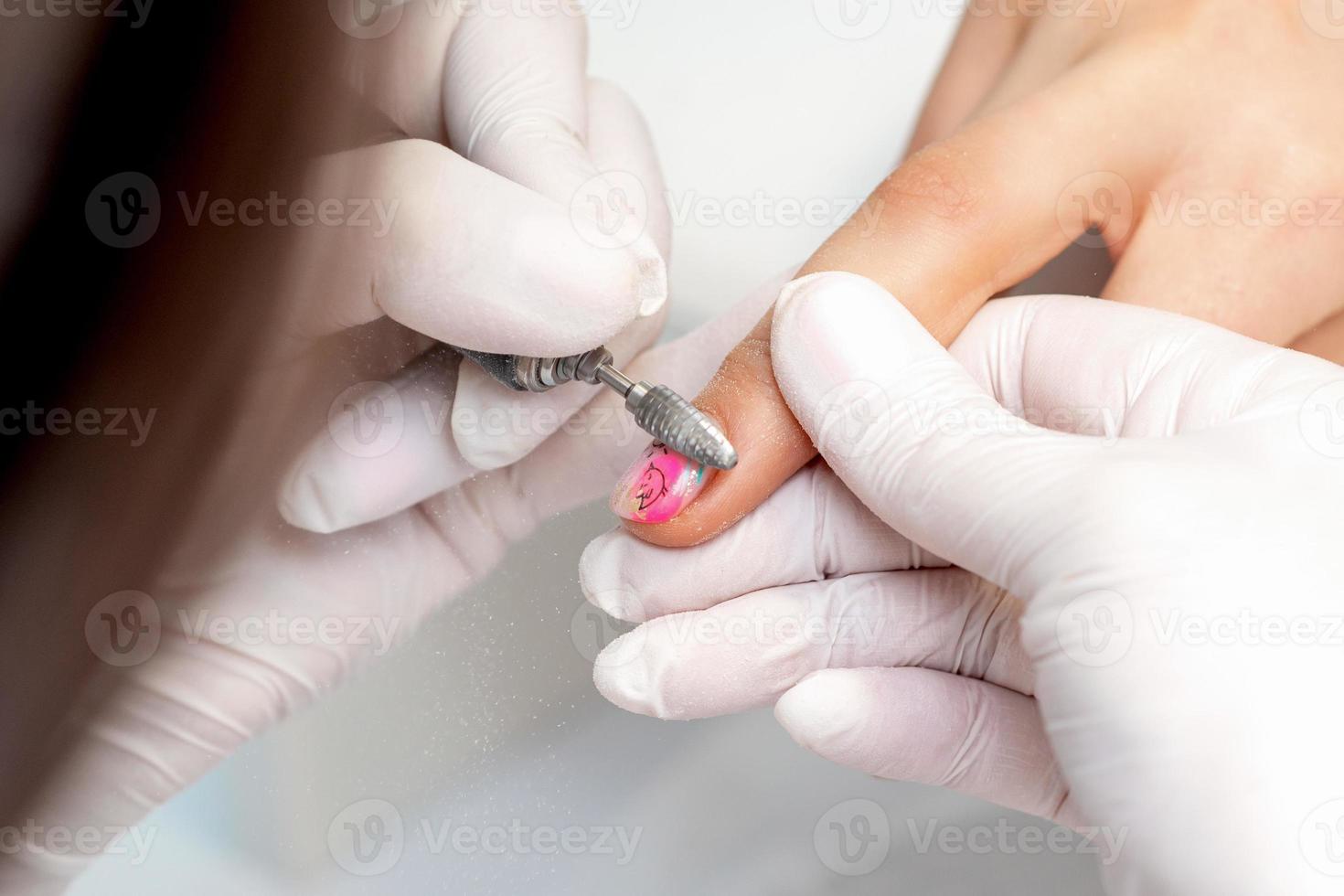 Manicure master uses an electric nail machine photo
