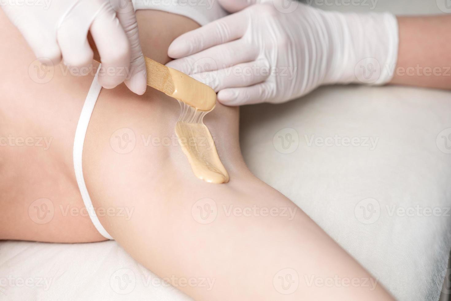 Cosmetologist applying wax paste on armpit photo