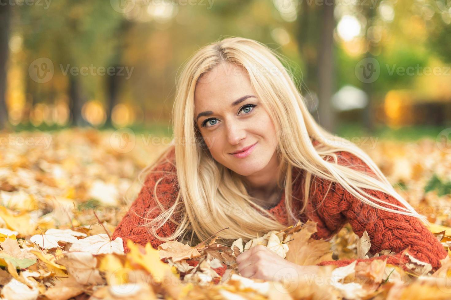 Woman lies down on leaves at the autumn park photo