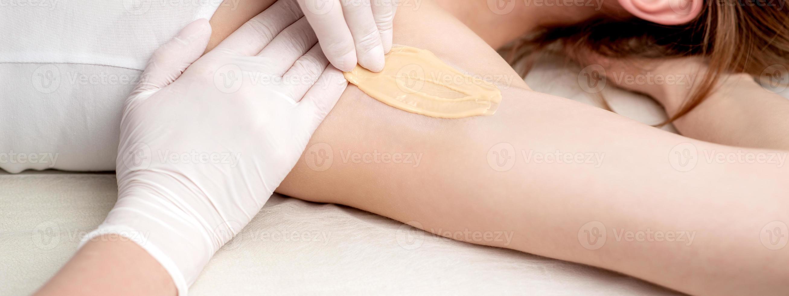 Cosmetologist applying wax paste on armpit photo