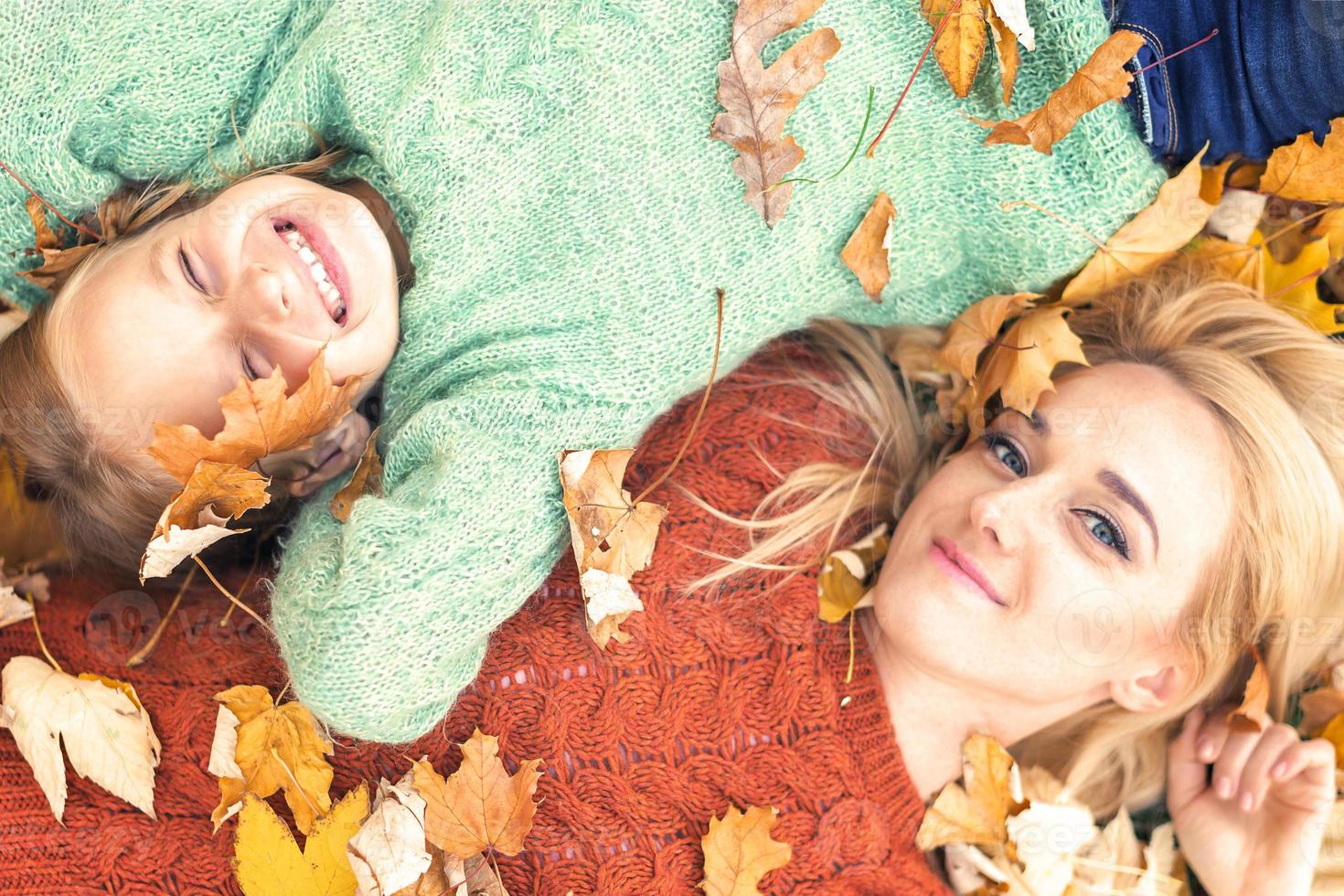 niña y mamá acostadas en hojas de otoño foto