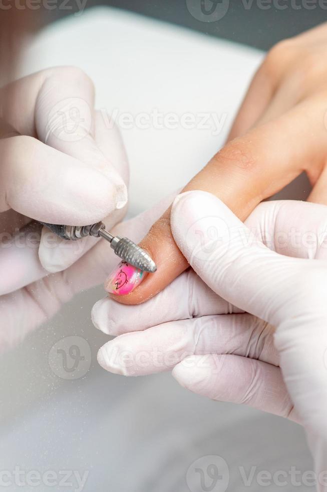 maestro de manicura utiliza una máquina de uñas eléctrica foto