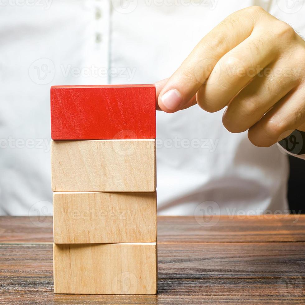 Man builds a tower of blocks. Emphasize significance, set attention. Create a plan order. Contract agreement road map. Organization and systematization, step by step instructions. Leadership concept. photo