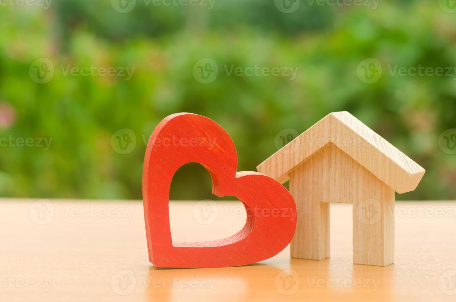 House with a red wooden heart. House of lovers. Affordable housing for young families, support program. Parental hospitable home. Housing construction of your dreams. Buying and renting real estate. photo