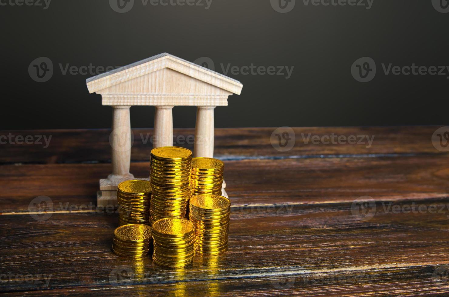 Bank building and coins stacks. State debt. Budget. Tax collection. Investments in education, museums and libraries, government institutions. Bank capitalization. Financial system, commerce and trade. photo