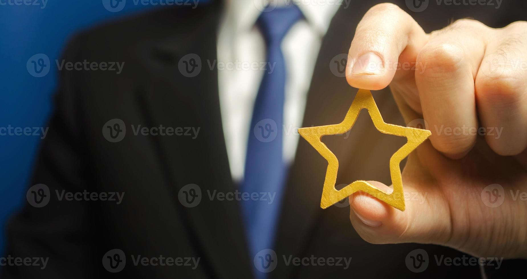 Man holds a golden star in his hand. Symbol of success and excellence. Good reputation, prestige, high recognition. Status, rating. Good ratings and reviews. VIP. Job promotion and career growth. photo