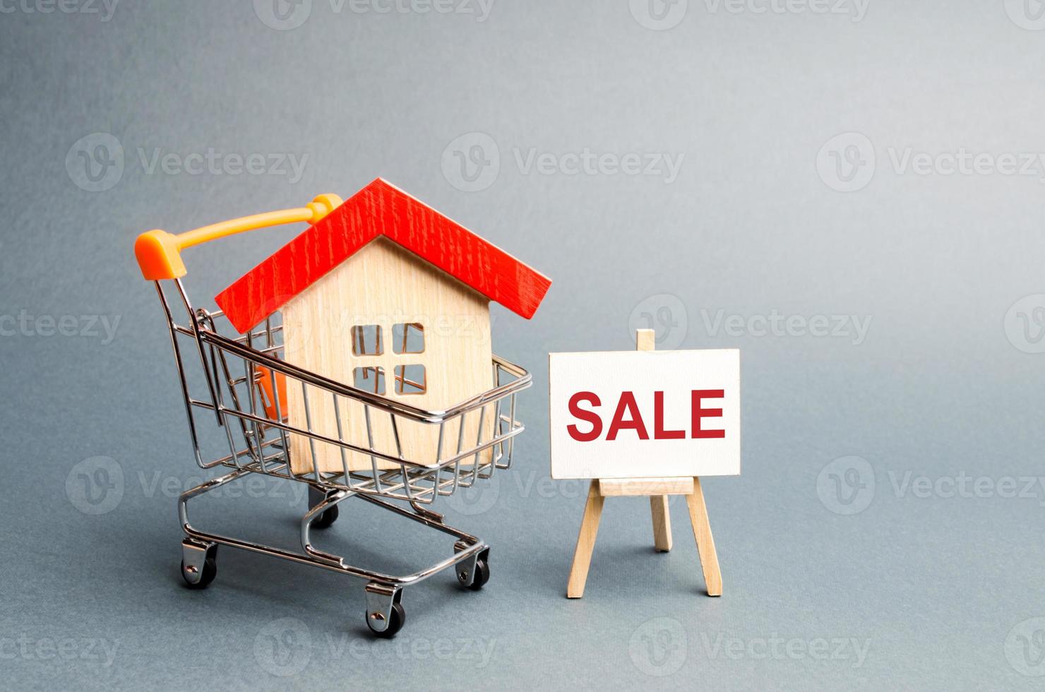 Supermarket cart with houses and a Sale Poster. The concept of selling a home, real estate services or buying from the owner. Buying and selling real estate, property, apartments. Selective focus photo