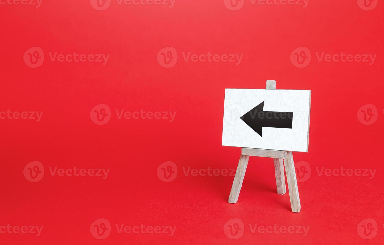 Left arrow easel sign. Direction pointer. Hint, help in navigation. Minimalism. Advertising and attracting attention. Redirecting traffic. Short road. Point at, show the way. Copy space photo