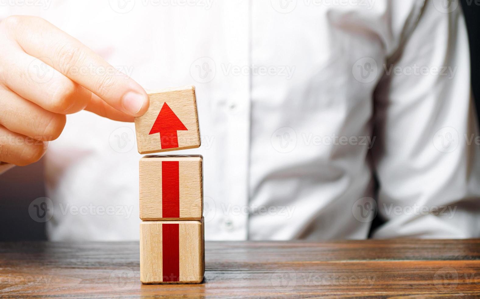 Man collects a tower of blocks with an arrow. Step-by-step career growth. Concept of development to new levels. Business expansion. Improving qualities and skills. Rising requirements and standards. photo